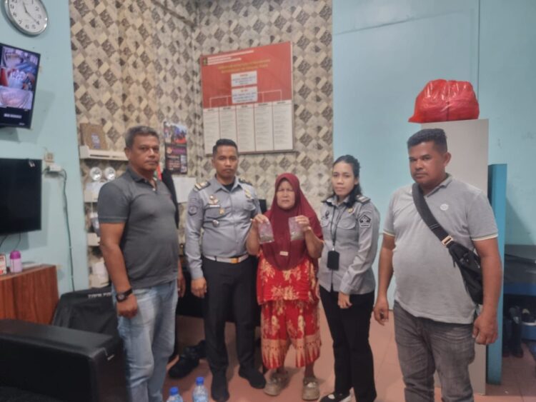 Ibu Berinisial R Memperlihatkan Barang Bukti Ganja Didampingi Dua Pejabat Rutan Tanjung Pura Beserta Dua Pihak Kepolisian.(Doc/Foto : Humas Rutan Tanjung Pura)