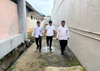Kepala Urusan Umum (Kaur Umum) Lapas Kelas IIB Padangsidimpuan, Baginda Nauli Ritonga (paling kanan), bersama stafnya, melaksanakan pengecekan rutin kondisi fisik bangunan dan area drainase di jalur branggang Lapas.(Doc/Foto : Humas Lapassid)
